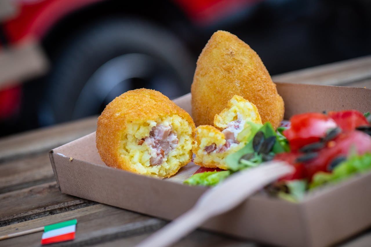 Close-up of arancini with a fresh salad, captured outdoors in natural light.